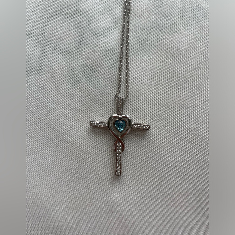 Silver cross necklace with aquamarine stone in the middle